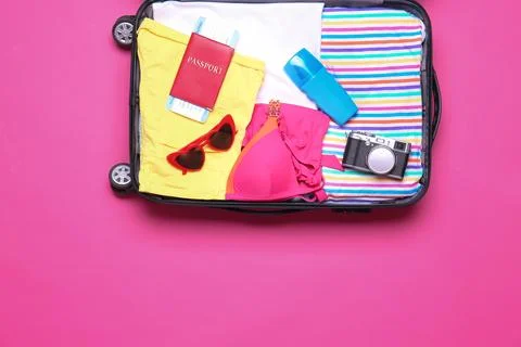 Open suitcase with beach objects on pink background, top view Stock Photos