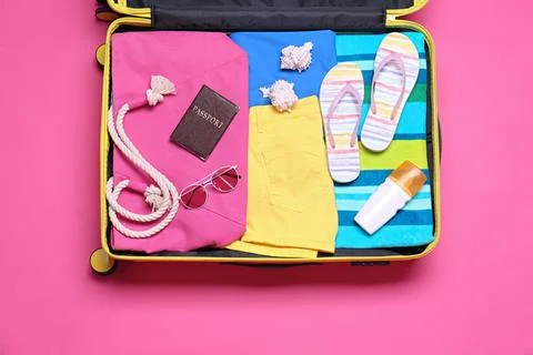 Open suitcase with beach objects on pink background, top view Stock Photos