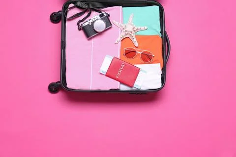 Open suitcase with beach objects on pink background, top view Stock Photos