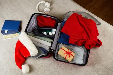 An open suitcase with clothes, documents, a gift, a Santa Claus hat Stock Photos