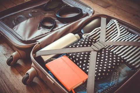 Open suitcase full of clothes isolated on wooden background Foto stock