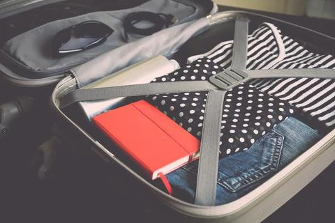 Open suitcase full of clothes isolated on black background Stock Photos