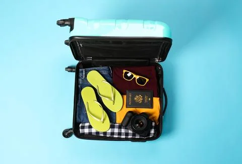 Open suitcase with traveler's belongings on color background, top view Stock Photos