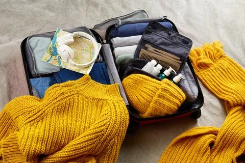 An open suitcase with warm clothes, documents and accessories 写真素材