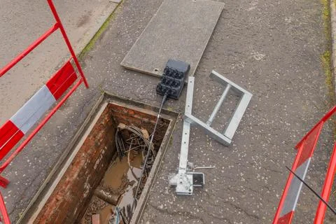 Open telecoms chamber in road with cable duct seal and barriers Stock Photos