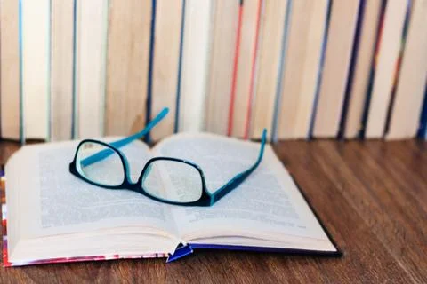 Open textbook, glasses, stack of old book on wooden table, education concept  Stock Photos