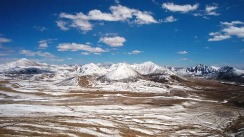 Open Tibetan mountain basin patterned with snow and brown earth Vidéo 345882268