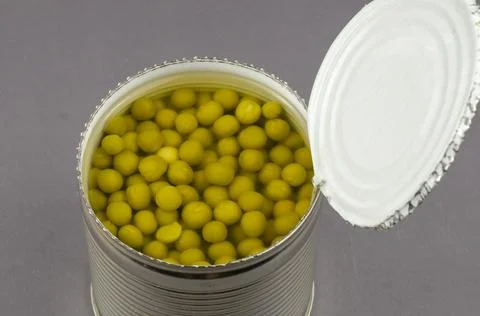 Open tin can on a gray background. Canned green peas. The can was opened with Stock Photos