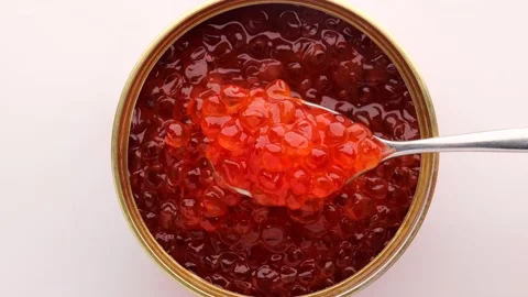 Open tin can with red caviar on a white background. The hand holds a spoon Stock Footage 232898727