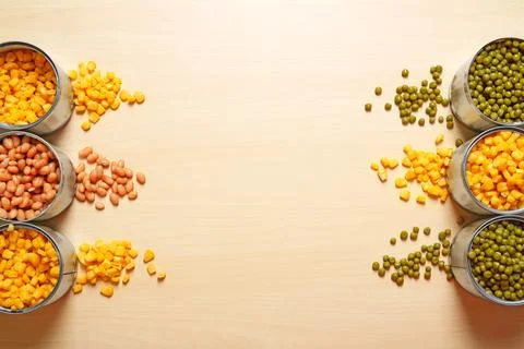 Open tin cans of conserved vegetables on wooden background, flat lay with spa Stockfoto's