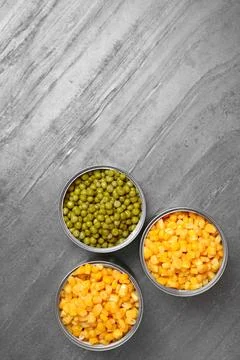 Open tin cans of conserved vegetables on grey table, flat lay with space for  写真素材