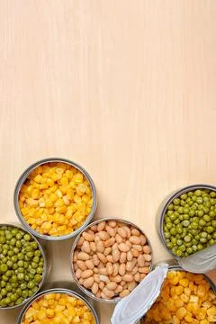 Open tin cans of conserved vegetables on wooden table, flat lay with space fo 写真素材