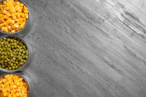 Open tin cans of conserved vegetables on grey table, flat lay with space for  写真素材