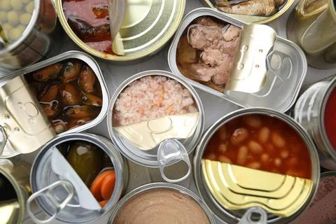 Open tin cans with different preserved products on table, flat lay 写真素材