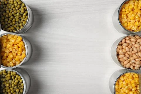 Open tin cans with different vegetables on light table, flat lay. Space for t 写真素材