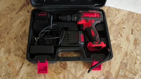 Open tool case with power drill on table in garage, workshop. Electric tools for Stock Footage 322893541