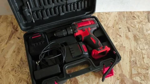 Open tool case with power drill on table in garage, workshop. Electric tools for Stock Footage 322893585
