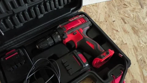 Open tool case with power drill on table in garage, workshop. Electric tools for Stock Footage 322893630