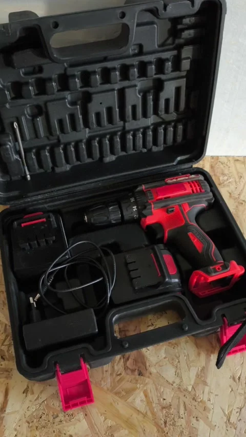 Open tool case with power drill on table in garage, workshop. Electric tools for Stock Footage 322893653
