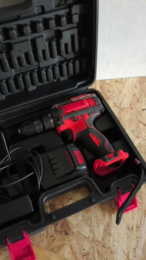 Open tool case with power drill on table in garage, workshop. Electric tools for Stock Footage 322893694