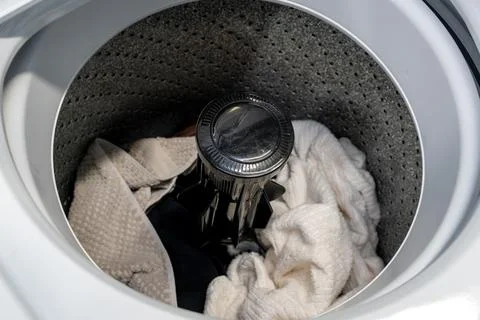 Open top-loading washing machine drum filled with dirty clothes Foto stock