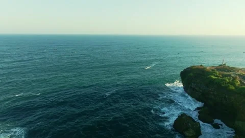 Open turquoise ocean meets a rugged coastal headland in a high aerial view .. Video stock 341544498
