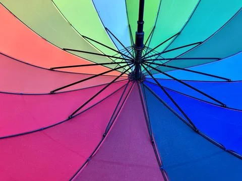 The open umbrella is bright, multi-colored, close-up. Background texture: c.. Photos