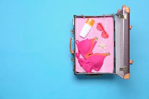 Open vintage suitcase with beach objects on blue background, top view. Space  Stock Photos