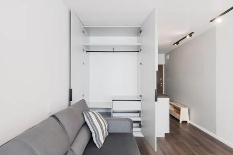 Open Wardrobe and Grey Sofa in Minimal Studio Apartment Interior With Moder.. Stock Photos