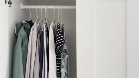 Open wardrobe with various colorful clothes hanging inside Stock Footage 340106423
