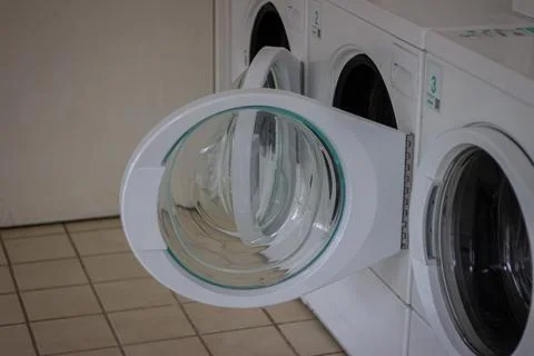 Open washing machine door in self service laundromat close up Stock Photos