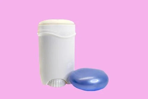 Open white bottle of solid deodorant with a blue cap on a pink background, co Stock Photos