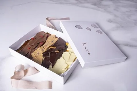 An open white box with assorted chocolate chips. Stock Photos