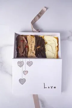 An open white box with assorted chocolate chips and the word love vertical. Stock Photos