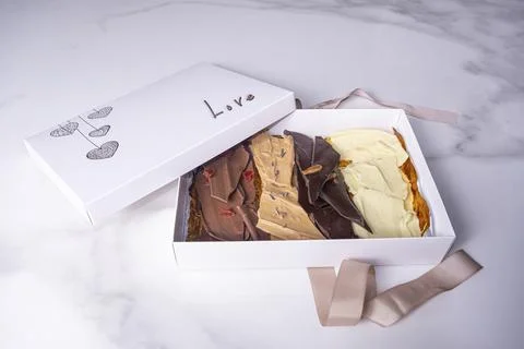 An open white box with assorted chocolate chips and the word love. Stock Photos