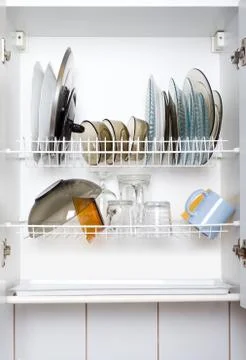 Open white dish draining closet with wet dishes Stock Photos