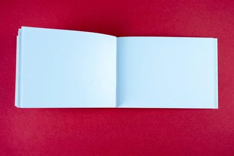 Open white horizontal notebook mock up on red paper background. Empty sketchbook Stock Photos