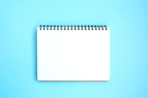 Open white notepad on a spiral on a bright blue background Stock Photos