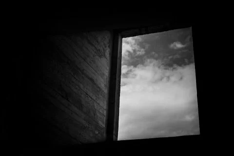 Open window on a framed cloudy sky, exposed concrete wall. Stock Photos