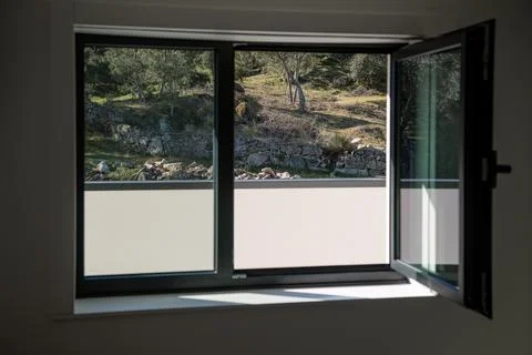 Open window framing a rural hillside with stone wall and trees, bringing nature Stock Photos