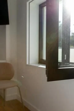 Open window letting warm sunlight stream into a minimalist room Stock Photos