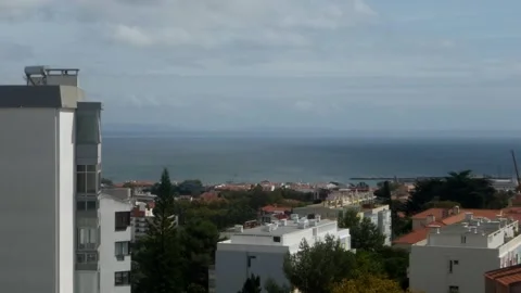 Open window with white curtain moving on the wind with view of city and ocean Stock Footage 251063279