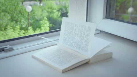 Open window on the windowsill lies an open book, a sunbeam shines on the pages Stock Footage 165248829