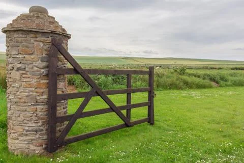 Open wooden gate into farmers green field.  Old stone pillar. Kirkwall Orkney Stock Photos