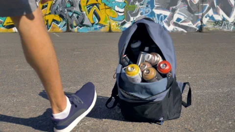 Opened backpack filled with spray paint is getting taken off the ground and Stock Footage 88900894