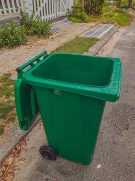 Opened big empty green plastic trash garbage bin in front of the modern house Stock Photos