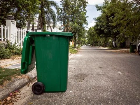 Opened big empty green plastic trash garbage bin in front of the modern house Stock Photos