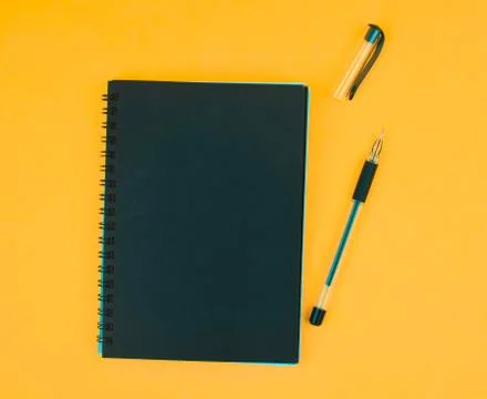 Opened black colored ball point pen placed beside a black colored paper diary Stock Photos