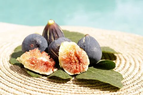 Opened black fig on a green leaf with other figs Stock Photos