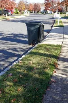 Opened black trash can on the side of the street by the curb in a residenti.. Stock Photos